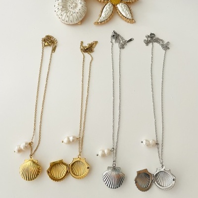 Conjunto de broche e colares com pendentes de conchas e contas brancas, em dourado e prateado.