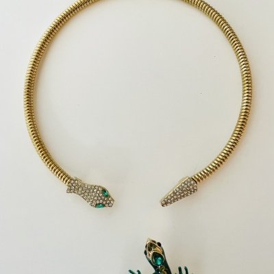 Colar rígido dourado com cabeça de cobra cravejada e broche lagarto verde