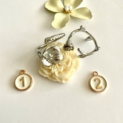 Anéis de metal prateado e pendentes dourados com números sobre flores artificiais