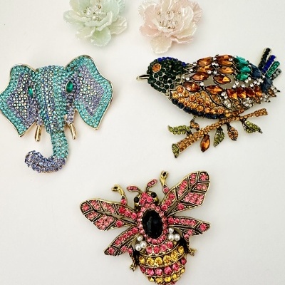 Broches decorativos em forma de elefante, pássaro e abelha com pedras coloridas e brincos florais pastel