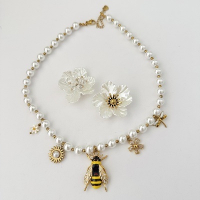 Colar com pérolas brancas e pendentes dourados sobre fundo branco