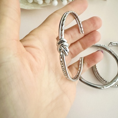 Pulseira prateada com nó decorativo na mão