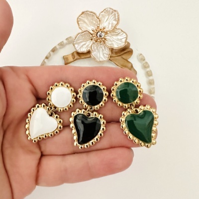 Três pares de brincos dourados com pedras coloridas em formatos redondo e coração