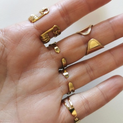 Mão com cinco argolas douradas diversas em fundo branco.