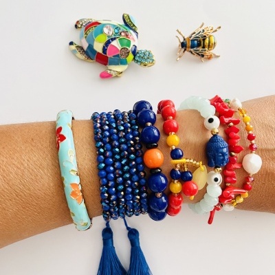 Pulseiras coloridas variadas em braço com tartaruga e abelha em esmalte colorido no fundo