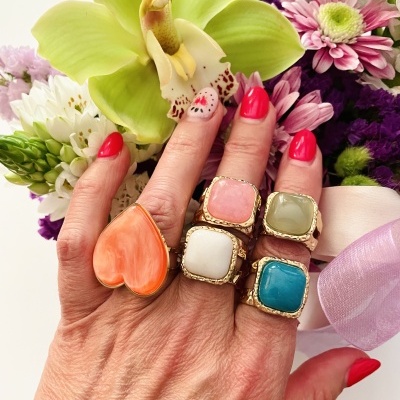 Mão feminina com anéis coloridos e flores