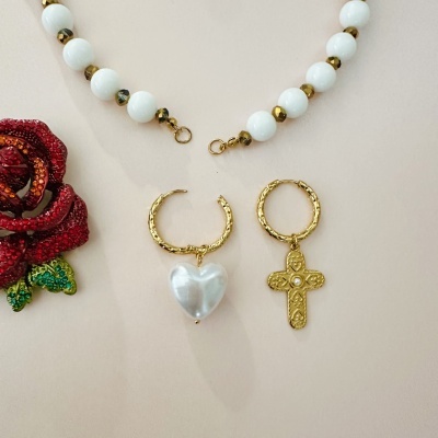 Colar de contas brancas com contas douradas e dois brincos dourados com pendentes, um coração e uma cruz