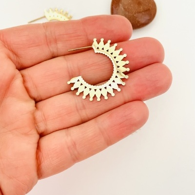 Brincos de argola dourados com padrão pontiagudo em mão