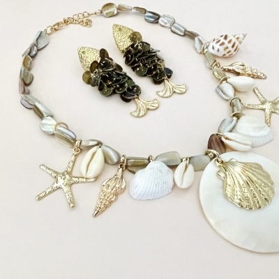 Colar com contas madre-pérola e pendentes de conchas e estrelas do mar, e brincos dourados design de peixe com pedras negras