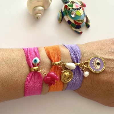 Pulseiras elásticas coloridas com pendentes dourados e coloridos no pulso