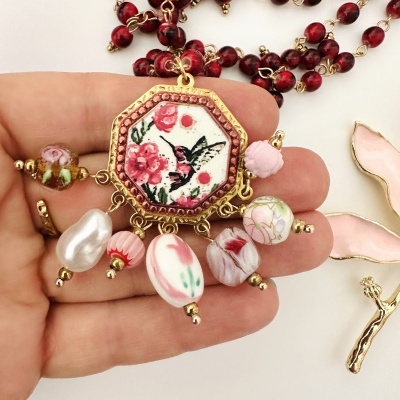 Colar com pendente octogonal com flores e beija-flor, contas diversas cor de rosa e branco, corrente com contas vermelhas.