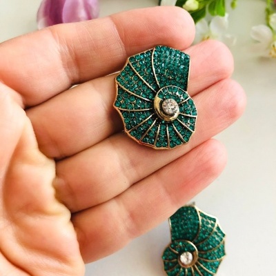 Brincos em espiral verde-esmeralda com detalhes dourados e pedra central transparente.