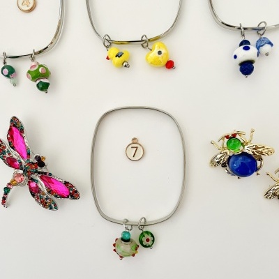 Pulseiras metálicas com pendentes coloridos e etiquetas numeradas