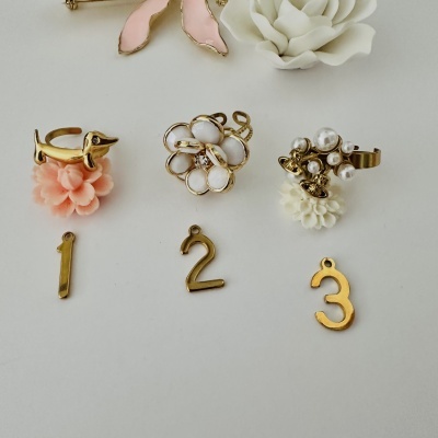 Anéis dourados decorativos com flores e pérolas sobre fundo branco