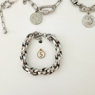 Pulseiras metálicas prateadas com medalhas e pingentes sobre fundo branco.