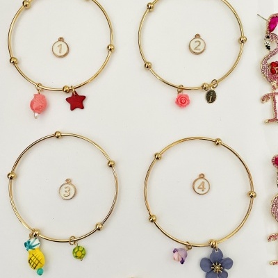 Pulseiras douradas com pendentes coloridos e números 1 a 4 sobre fundo branco