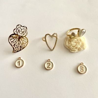 Três anéis dourados delicados com números 1, 2 e 3 em pingentes brancos ao lado