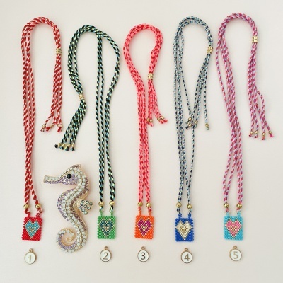 Cinco colares com cordões trançados coloridos e pingentes com padrões geométricos e pérolas