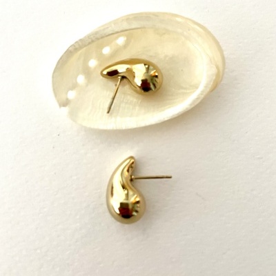 Brincos dourados em forma de gota com um em concha sobre fundo branco