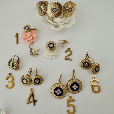 Conjunto de joias douradas com detalhes azuis e números em fundo branco