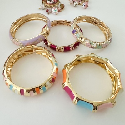 Conjunto de cinco pulseiras douradas com esmalte colorido sobre fundo branco