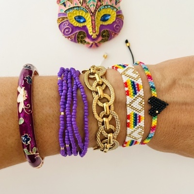 Pulso com cinco pulseiras coloridas e máscara decorativa de cabeça de gato na parede