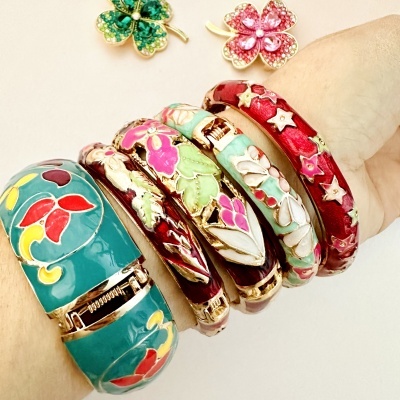 Pulseiras rígidas coloridas com padrões florais em esmalte e dourado no braço