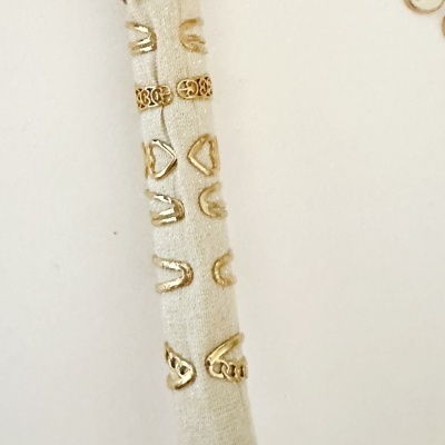 Suporte de tecido bege com vários anéis dourados expostos