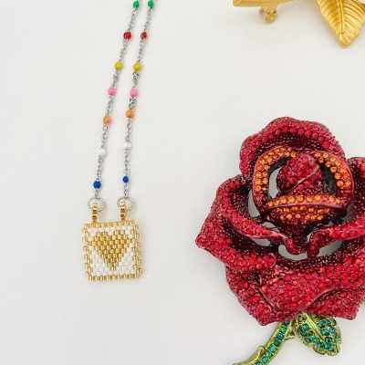 Colar com pendente dourado e broche de rosa vermelha com pedras brilhantes