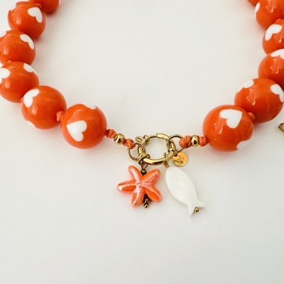 Colar com contas laranja com corações brancos, fecho dourado e pendentes de estrela do mar e peixe