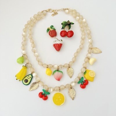 Conjunto de colares e broches com temas de frutas e folhas douradas