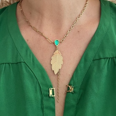 Colar dourado com pendente de folha e pedra verde usado com camisa verde