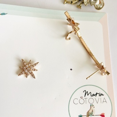 Conjunto de brincos dourados com pedras sobre cartão com logo Maria COTOVIA
