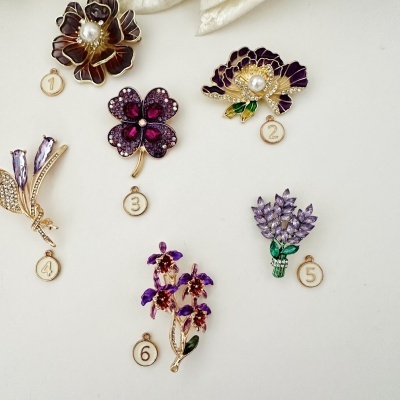 Pins de joalharia floral em metal dourado com esmalte roxo e pedras brilhantes