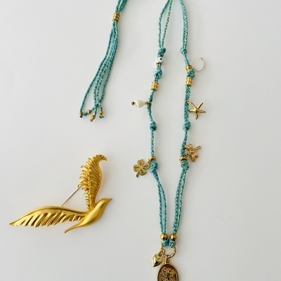 Colar azul com pingentes dourados e alfinete dourado em forma de pena