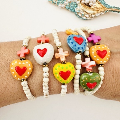 Pulseiras coloridas com corações e cruzes sobre um pulso