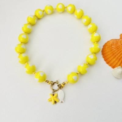 Pulseira amarela com corações brancos e pendentes em forma de estrela do mar e peixe