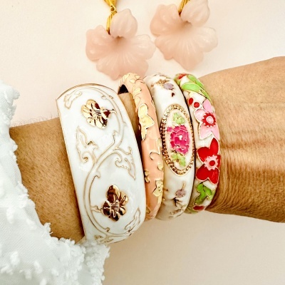 Pulseiras coloridas com padrões florais e dourados no pulso