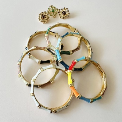 Sete pulseiras coloridas e três botões decorativos dourados sobre fundo branco