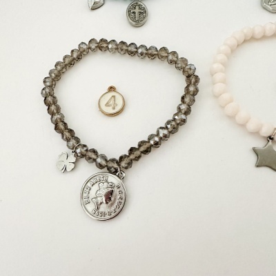 Pulseira cinzenta com pendentes de trevo e moeda, medalha dourada número 4 e pulseira cor-de-rosa com pendente de estrela
