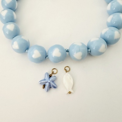 Colar azul com corações brancos e dois pendentes cerâmicos em fundo branco