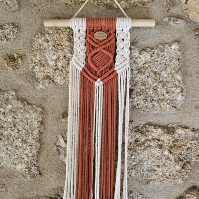Tapeçaria de parede em macramé creme e terracota pendurada numa vara de madeira