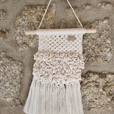 Tapeçaria decorativa de algodão pendurada numa parede de pedra