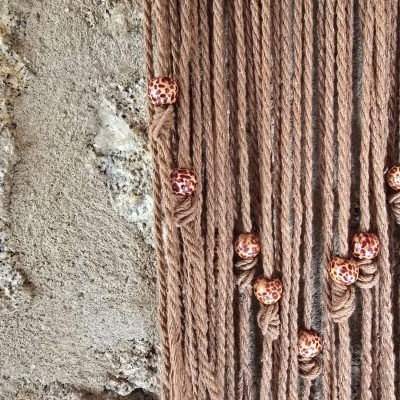 Cortina de cordas castanhas com contas de madeira em parede de pedra cinzenta
