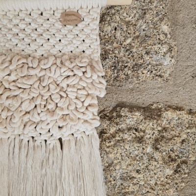 Tapeçaria decorativa de algodão cru com franjas em parede de pedra com etiqueta Mona Macrame
