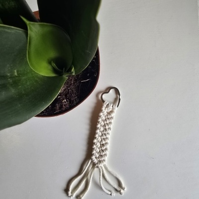 Chaveiro macramé branco com argola metálica em superfície branca