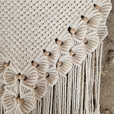 Tapeçaria de macramé em algodão cru com bolinhas de madeira e franjas