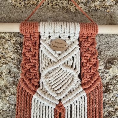 Tecelagem em macramé com cordas terracota e cru e placa de madeira com texto 'Maria Marianne'