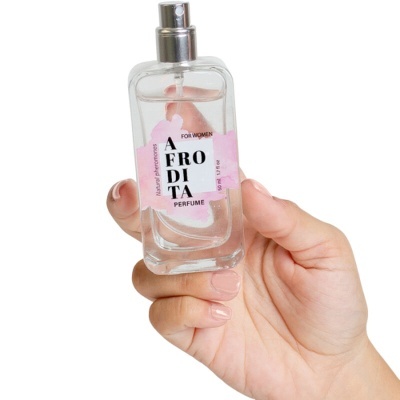 Frasco de perfume transparente AFRODITA com pulverizador prateado numa mão