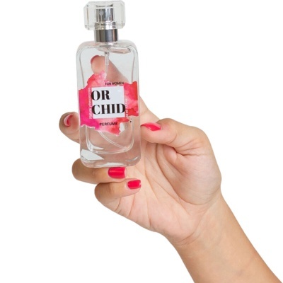 Frasco de perfume transparente com rótulo ORCHID PERFUME na mão feminina